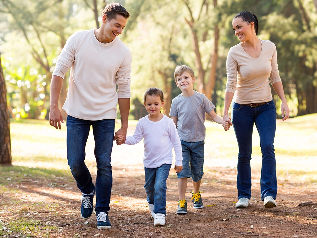 Happy young family walking through the park